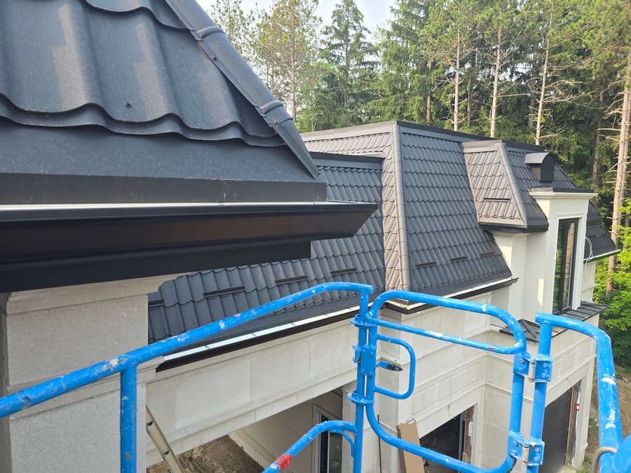 Black seamless eavestrough along a tile roof edge